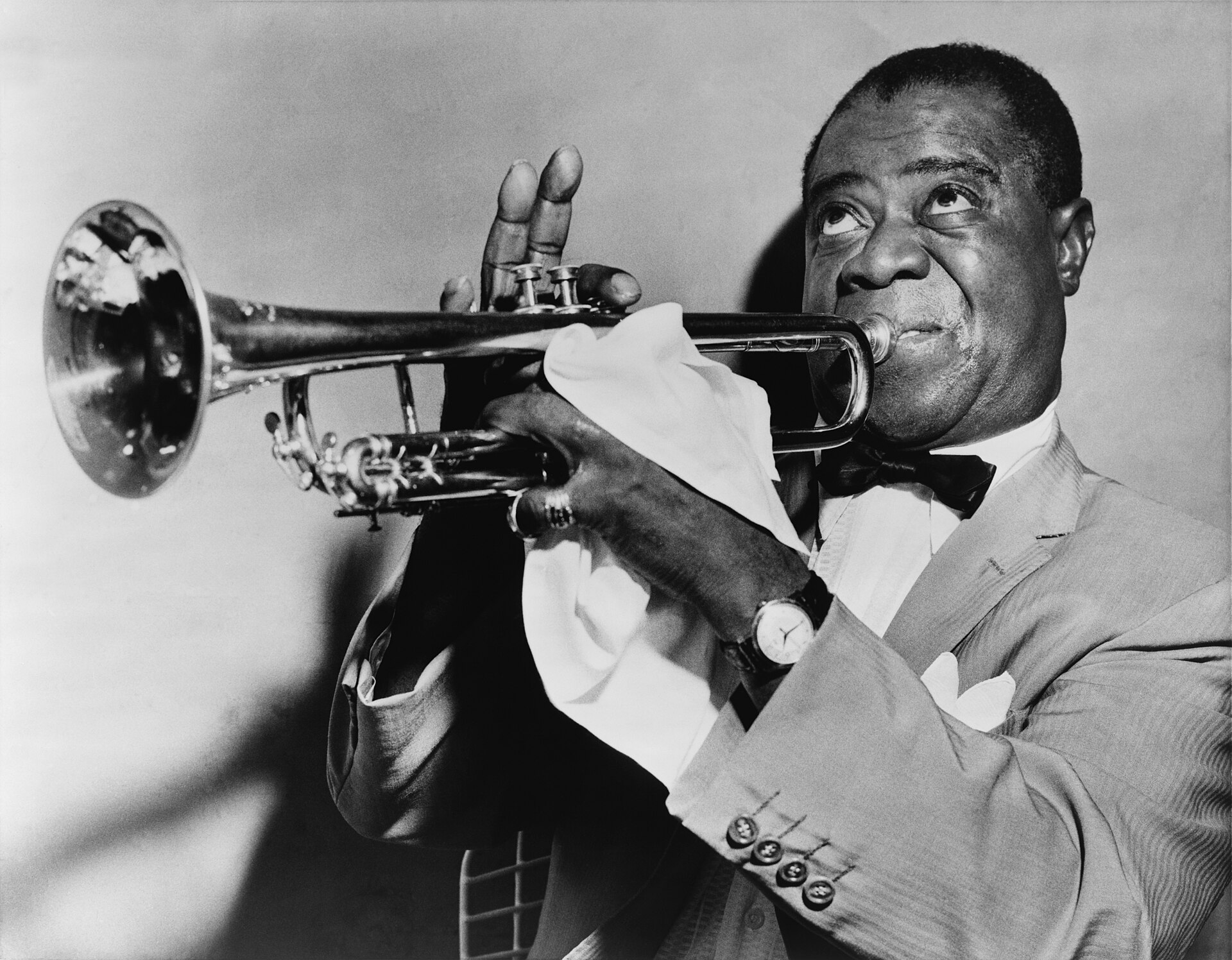 Portrait photograph of jazz musician Louis Armstrong holding his trumpet.